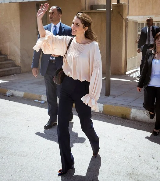 Queen Rania visited the Ballas Secondary School for Girls in Ajloun Governorate. Queen Rania style; wore Valentino blouse and Prada clutch bag