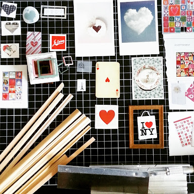 Flat lay of a selection of lengths of miniature picture framing, a hobby saw and mitre box and a collection of small pictures with hearts in them with a stack of one-twelfth scale frames.