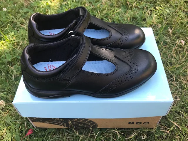 A pair of black t-bar school shoes on a shoe box