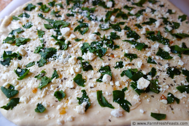 image of feta cheese and fresh spinach on top of pizza dough