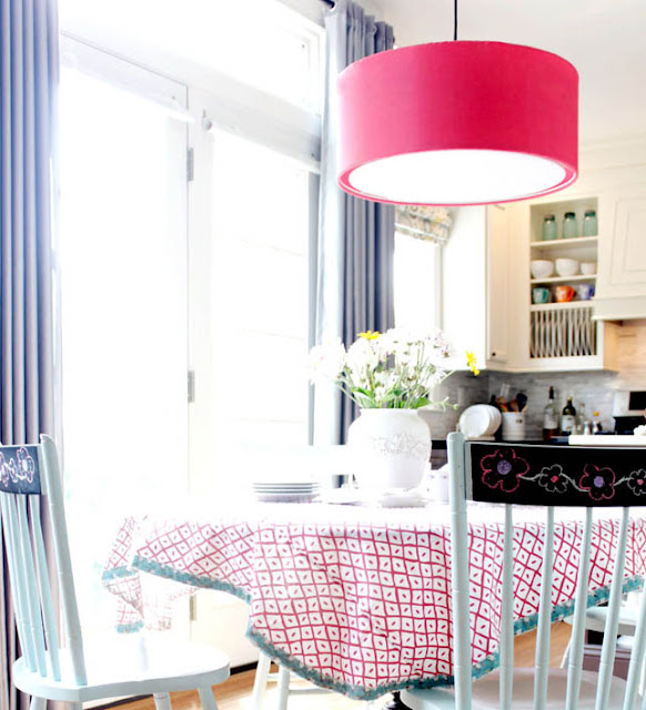 kitchen table with tablecloth, pink drum light, blue chairs