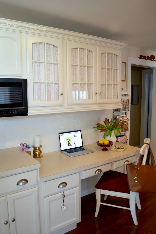 Charming kitchen desk area with fabric covered cabinets