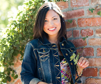 Photo of food blogger Liren standing outside next to a brick wall holding a plant