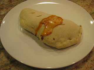 calzone with cheese oozing out in image with poor lighting