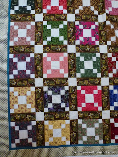 Reproduction fabrics in many colors alternate with muslin in this quilt.