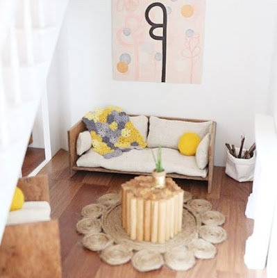 Modern dolls' house miniature lounge in pale shades, with grey and yellow accents, including a granny square rug.