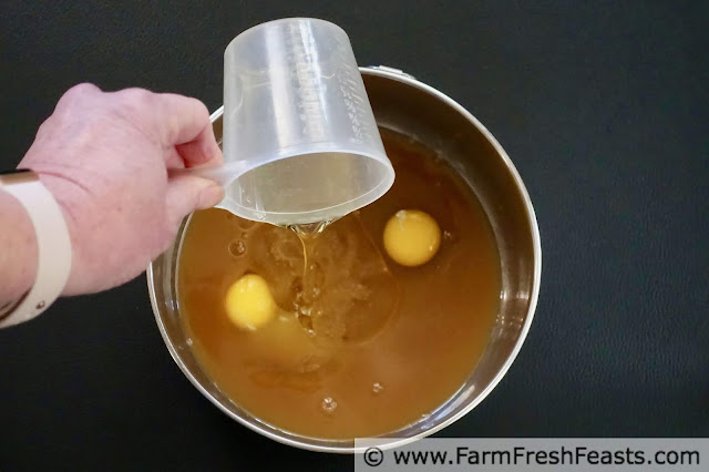 image of preparing wet ingredients for healthy apple cider donut muffins--pouring vegetable oil into bowl with eggs and reduced apple cider
