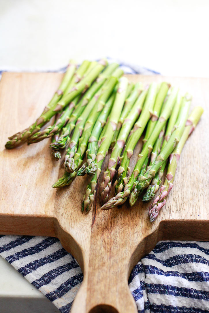 Asparagus Beautiful close-up photo of green asparagus on a cutting board with a blue and white striped kitchen towel.