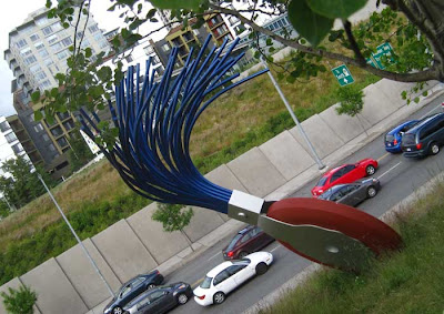 Giant typewriter eraser with round rubber disc and brush overlooking a stream of traffic below