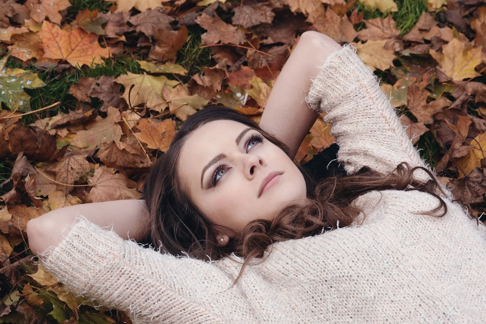 秋の落ち葉に仰向けの女性