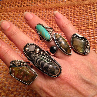 Image shows hand with five sterling silver and gemstone handcrafted rings.