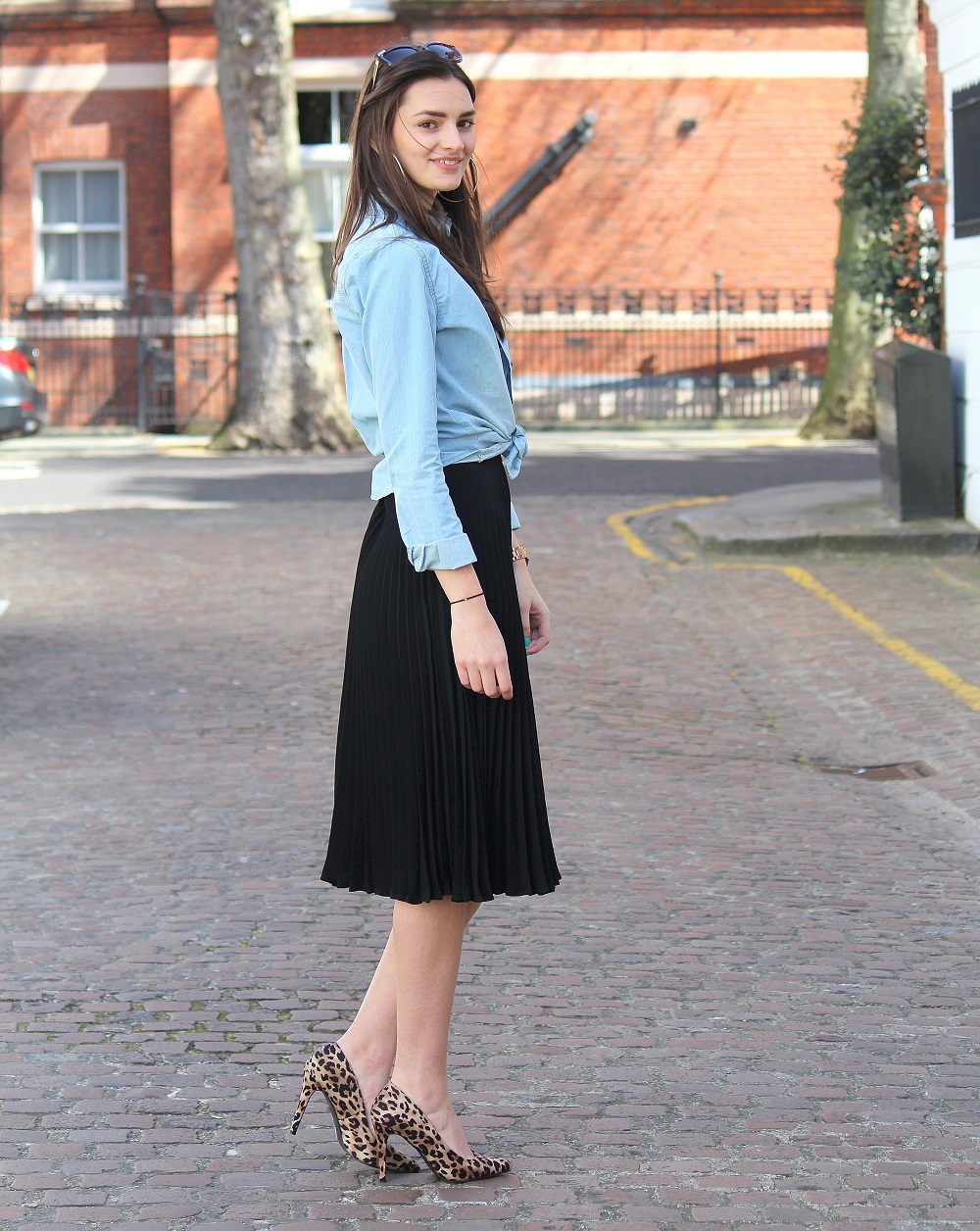 peexo fashion blogger wearing pleated midi skirt with lace bralet and denim shirt and leopard print heels and sunglasses in spring