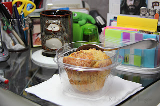Eating muffin at workstation.