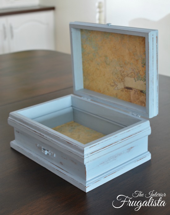 Pretty paper lined wooden jewelry box upcycled for remote control storage.