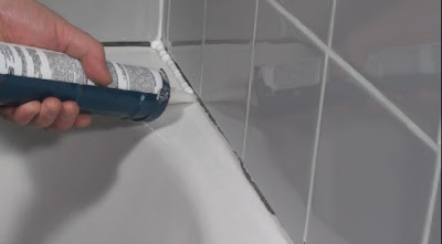 Caulking the edge of a tub and shower surround with fresh grout between the tiles
