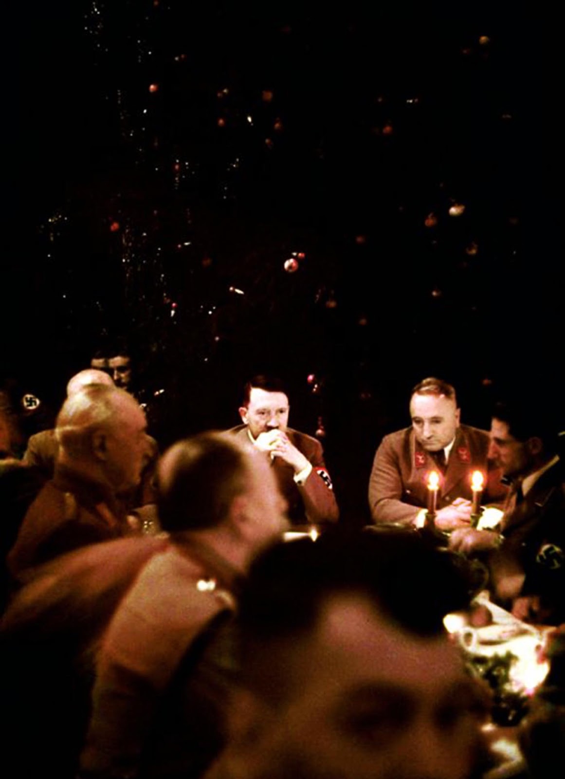 Grasping his knuckles, a pensive Hitler looks down the table at dozens of Nazi soldiers at a Christmas meal in Munich.