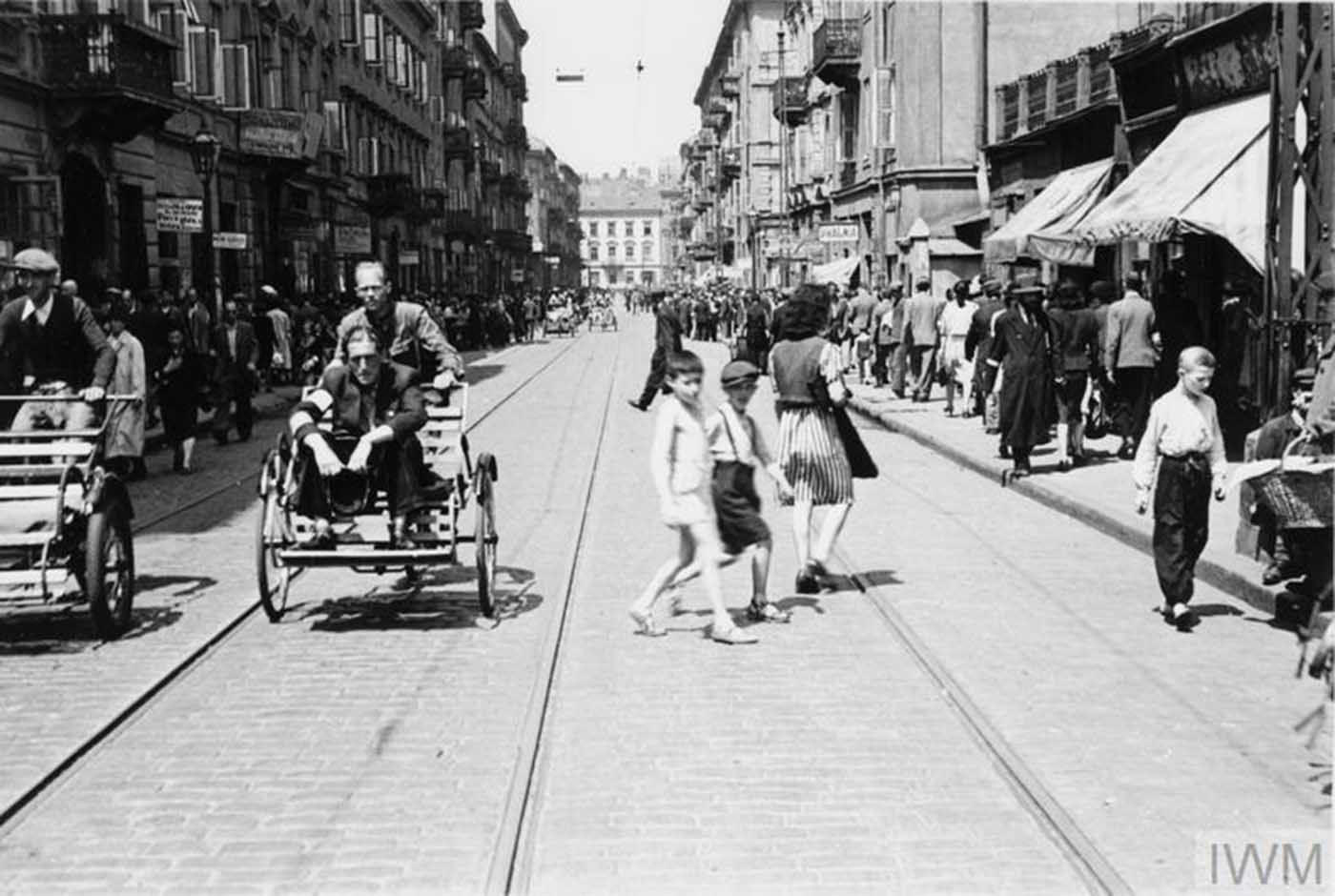 Crowds of pedestrians and street rickshaws in busy Karmelicka Street in the ghetto.