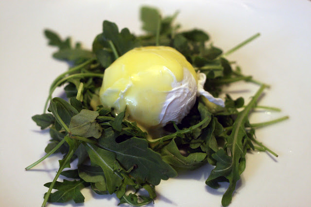 Poached eggs with hollandaise sauce on a bed of arugula
