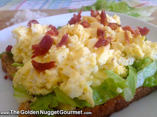 Egg salad topped with bacon on a piece of toast