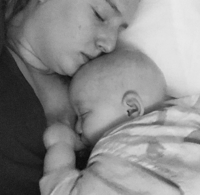 black and white photograph of a sleeping mother with a breastfeeding baby