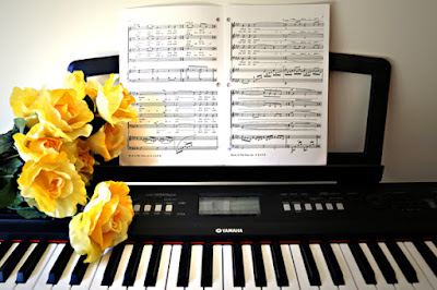 photo of yellow roses at piano with sheet music taken by chorale member E. Schneider