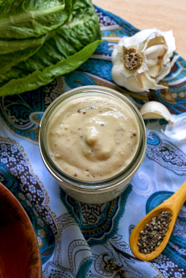 Homemade Creamy Caesar Dressing in a small mason jar on a white and teal paisley background.