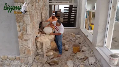Dia 19 de setembro de 2016, Bizzarri trabalhando na construção da cascata de pedra, com pedra de rio, no lago das carpas com pedra do rio e pedregulho do rio em jardim de inverno na sala de estar da casa em condomínio em Atibaia-SP, com as paredes revestidas com pedra moledo.