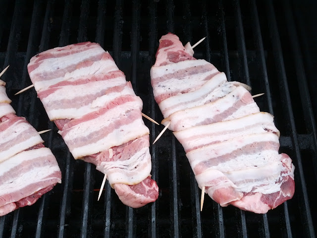 Bacon wrapped strip steaks on a grill