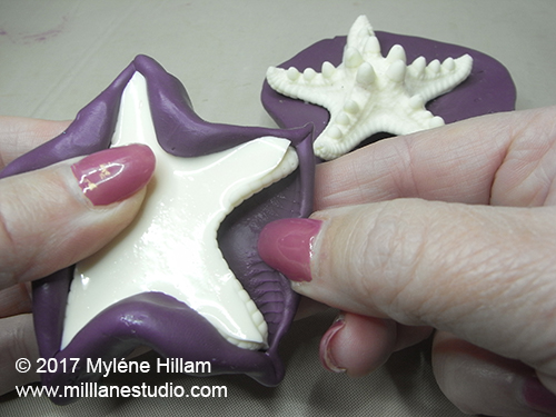 Gently removing the cured white resin starfish from the silicone mould.
