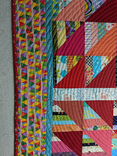 This shows part of the center, both borders, the pink binding, and the spiral quilting.