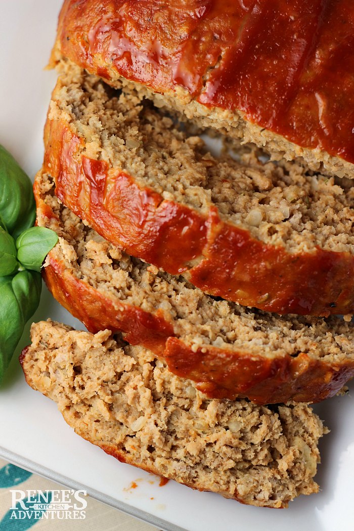 The Best Ground Turkey Meatloaf on a platter with basil to the side overhead view sliced from loaf