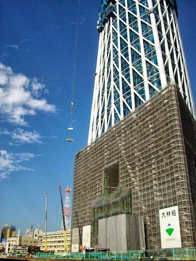 北十間川南側道路から見た建設中(174m)の塔体と吊り上げ作業の様子