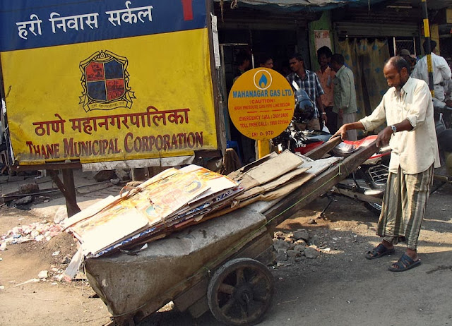 a cart loaded with cardboard and made of two wheels pulled by a man
