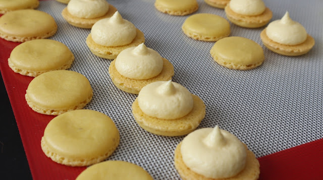 Lemon Macarons with a dollop of buttercream on the centre of each open half shell
