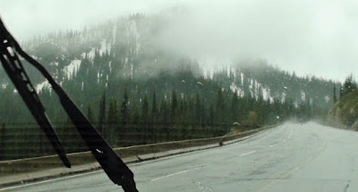 Windshield wiper clears rain to expose snow covered mountain