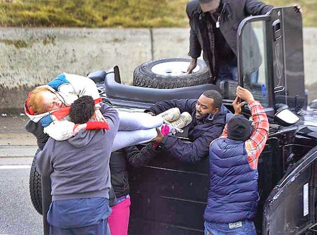 Detroiter Lance Swain, in vehicle, helps lift an elderly woman out of an overturned Jeep to other good Samaritans who stopped to help two women after an accident on southbound Lodge near the Howard exit in Detroit, Michigan on Tuesday, March 25, 2014. (Daniel Mears / The Detroit News)