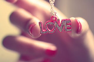 Imagen de una mano femenina sosteniendo una cadena con el nombre love