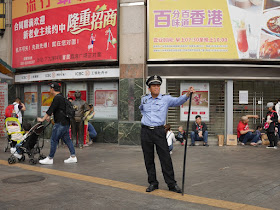Shangxiajiu Pedestrian Street security guard standing with a large black staff