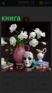 На столике около вазы с белыми цветами лежат книги и маска с кувшином 
