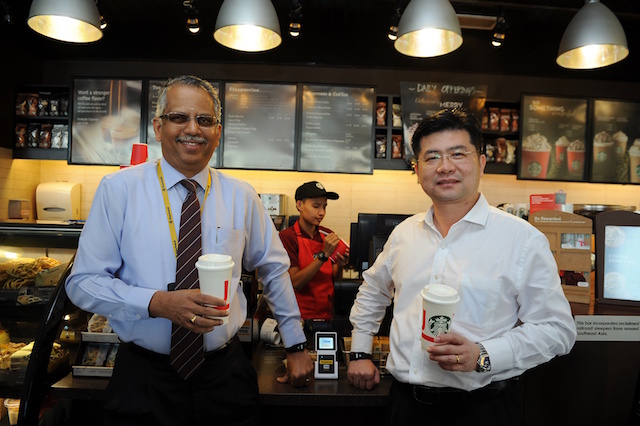 Maybank Group Head of Cards & Wealth, Mr. B Ravintharan and Visa Country Manager for Malaysia, Mr. Ng Kong Boon using their contactless wearables at Starbucks
