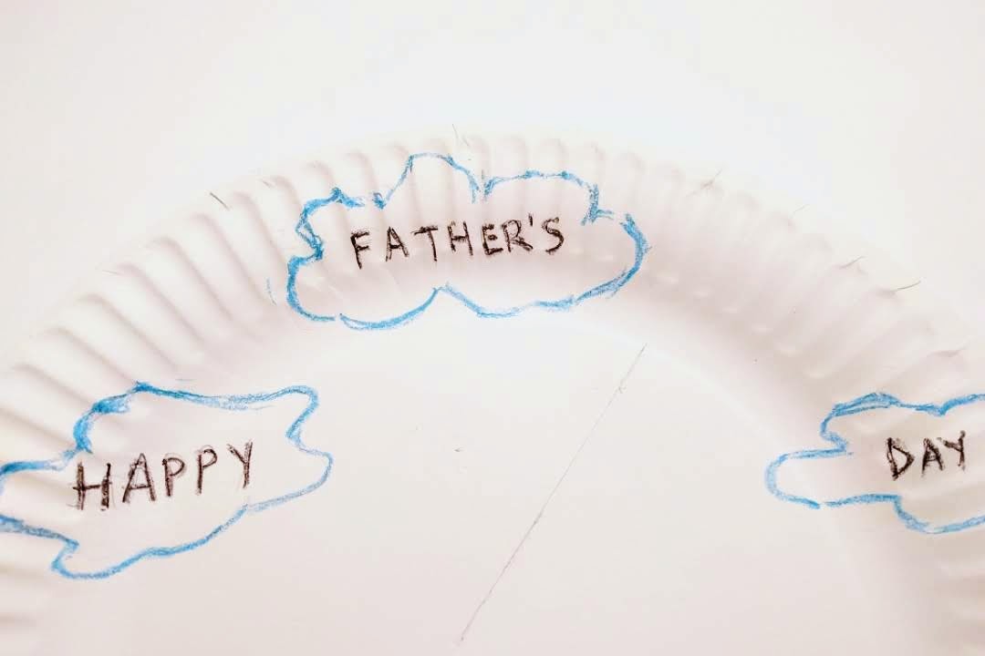 Writing Happy Father's Day message on the paper plate.