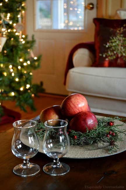 Two brandy glasses on table with apples on a green wreath