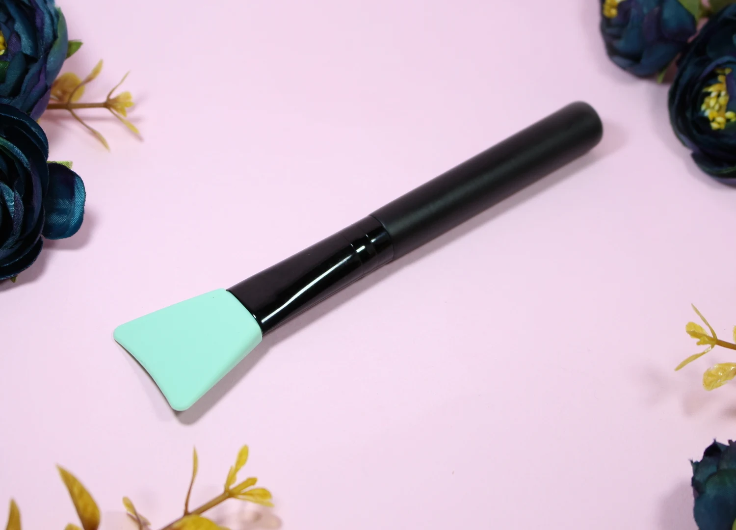 a close-up of silicone brush for face mask on a rosy background