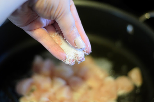 A hand seasoning the chicken in the pan with salt. 