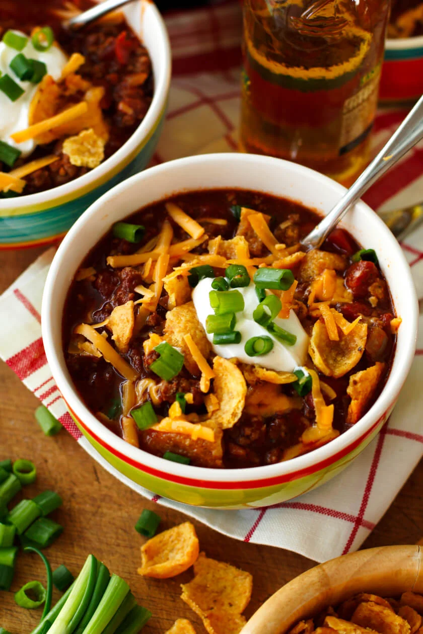 This Classic Slow Cooker Beef Chili is super easy to make, family-friendly, and perfect for feeding a crowd.  Load it up with all of your favorite chili toppings like cheddar cheese, Fritos corn chips, and cool sour cream! #chili #slowcooker #crockpot