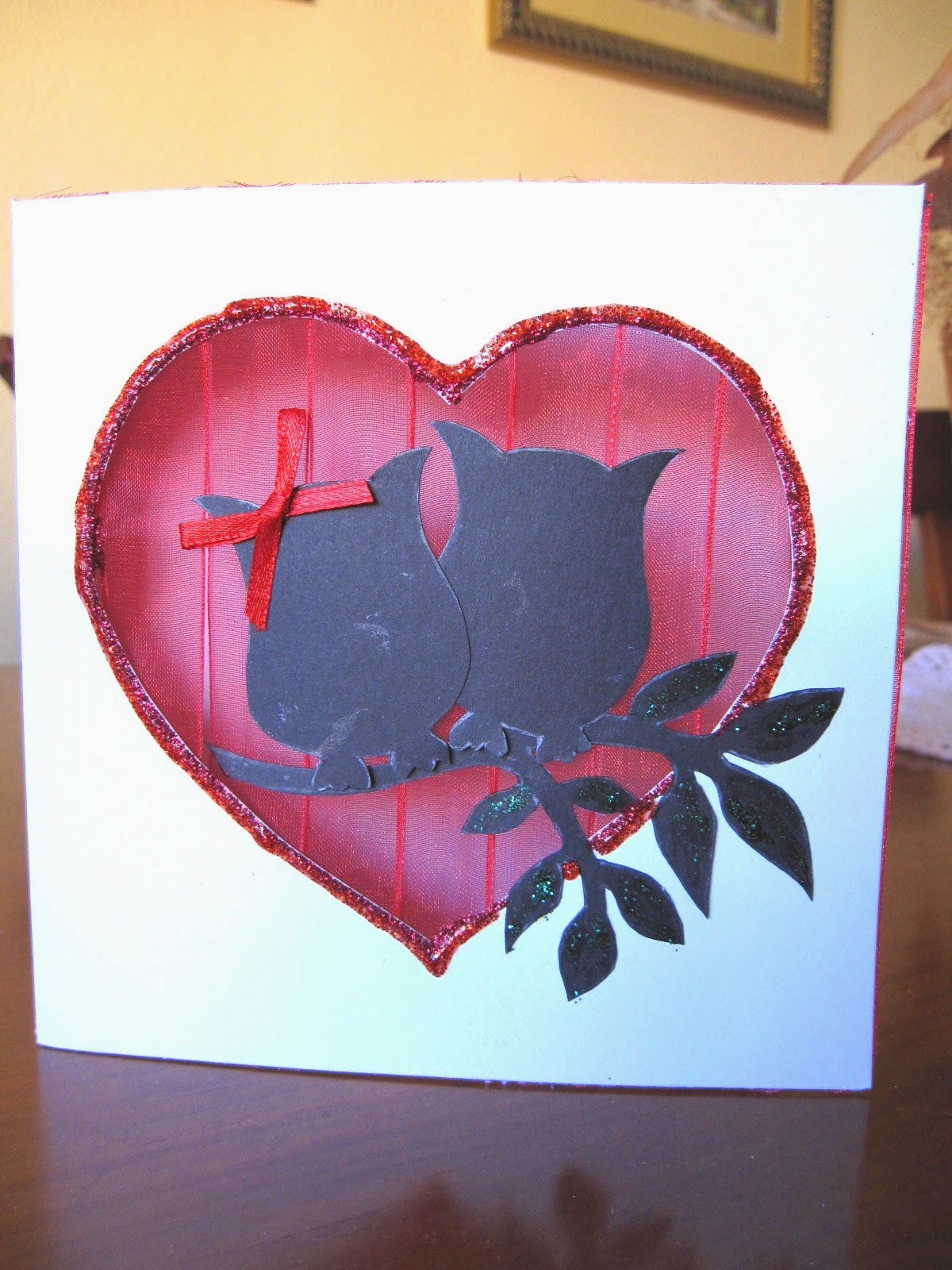 tarjeta de scrapbooking para San Valentín, luna roja con siluetas de búhos enamorados y rama y detalles de glitter glue rojo y verde