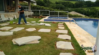 Bizzarri organizando para executar os caminhos de pedra no jardim em volta da piscina sendo a execução do caminho de pedra Carranca tipo cacão com junta de grama em casa em condomínio na represa de Piracaia-SP.