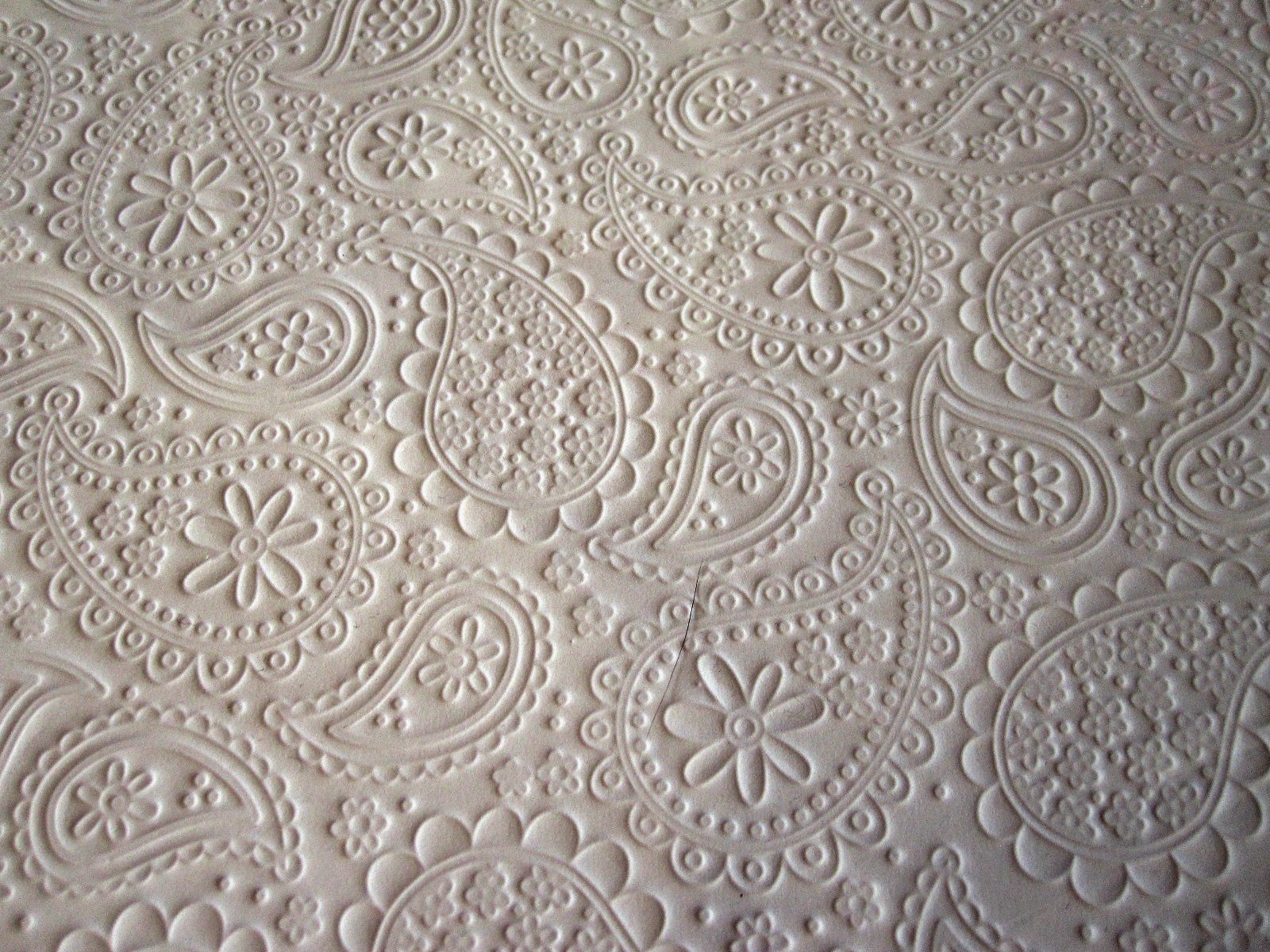Scrapbooking paper embossed with a paisley and daisy pattern.