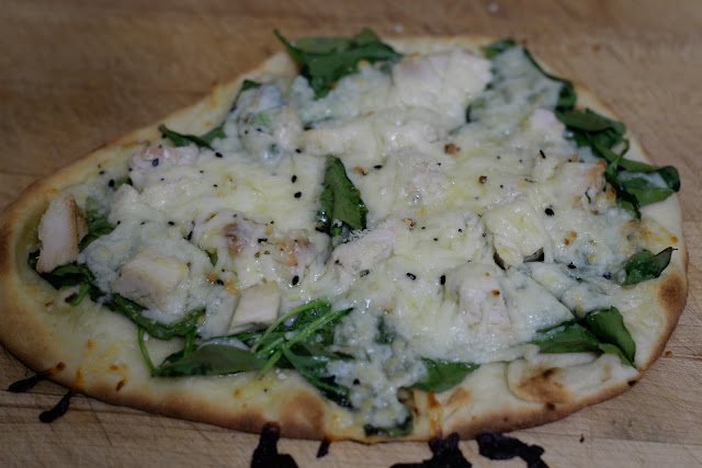The finished Chicken and Spinach Naan Bread Pizza on a cutting board. 