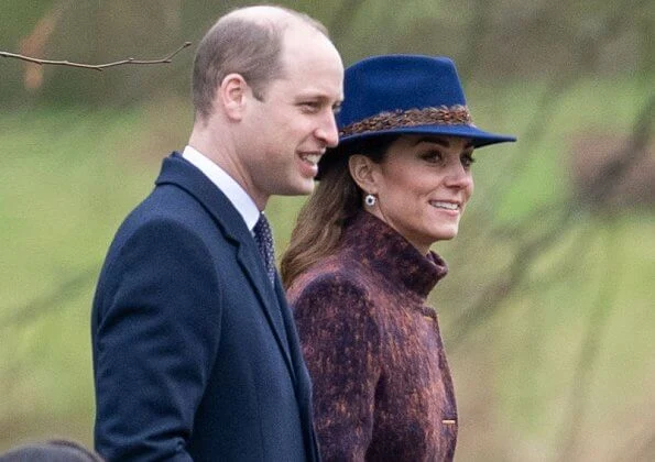 Kate Middleton wore a funnel neck coat, Stuart Weitzman knee-high boots,  feather fedora by Hicks and Brown, and carries Jaeger bag